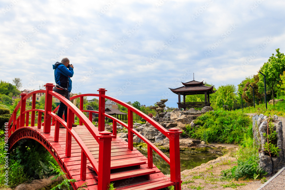 Travel photographer man with professional camera taking photos of Japanese garden Travel photographer man with professional camera taking photos of Japanese garden