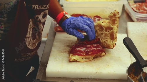 Preparation of sandwich or focaccia stuffed with artisan cured meats and other ingredients in oil. Food festival held in the alleys of Cisternino in 2019 before the Covid-19 pandemic. Apulia. Italy photo