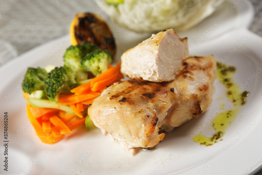 Roasted chicken breast served with a lettuce salad garnished with broccoli, carrot, pumpkin, and lemon juice.