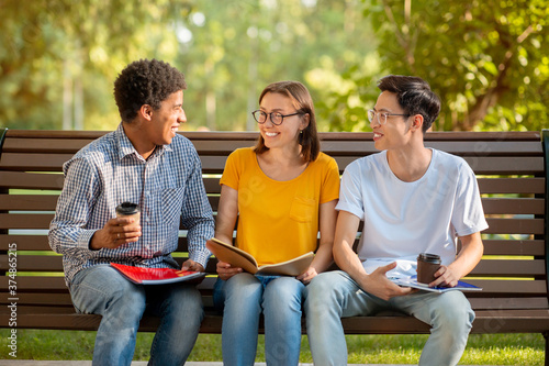 Multicultural Millennials Talking Sitting On Bench Outside After College Classes © Prostock-studio