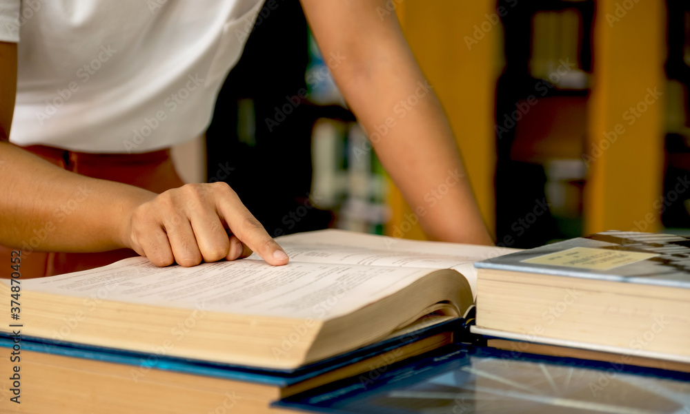 Young Asian female college students hand pointing to the book for research and learn from textbooks in the university library Young Asian female college students hand pointing to the book for research and learn from textbooks in the university library