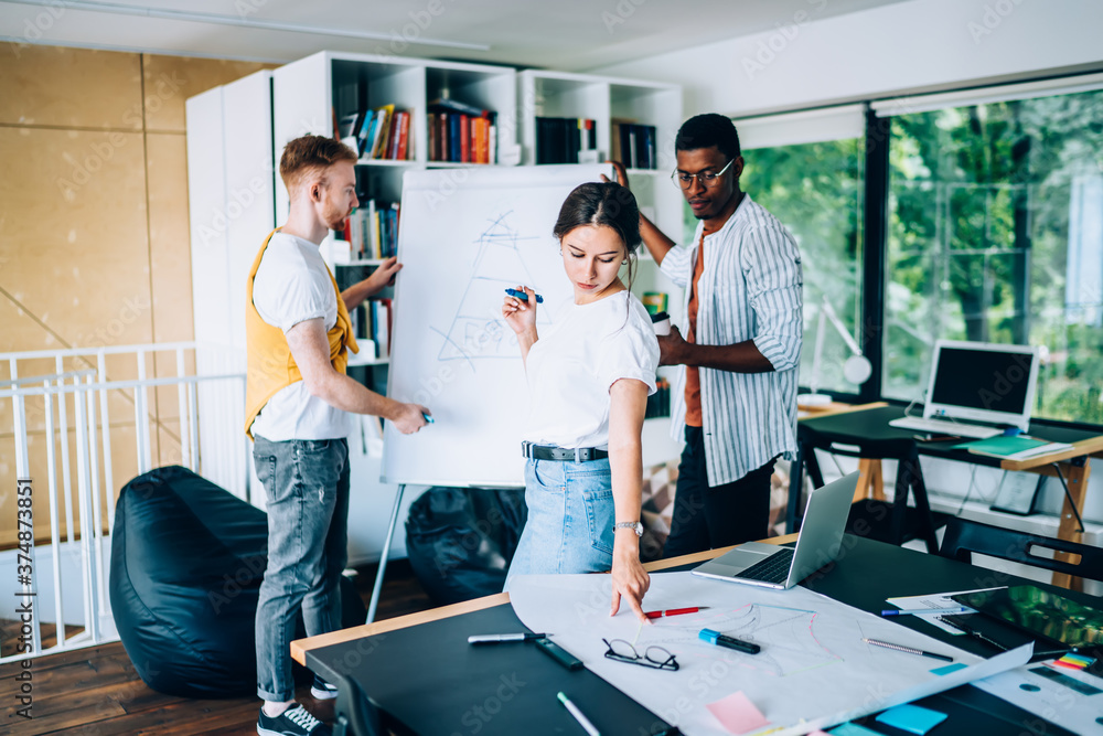 Obraz premium Young woman checking draft near diverse colleagues
