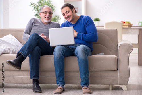 Father and son sitting on the sofa with computer