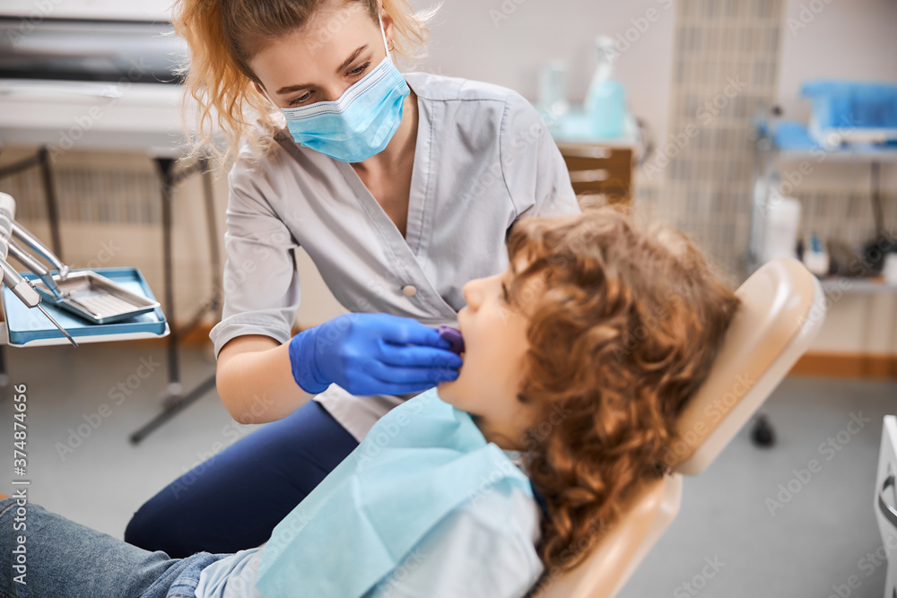 Dentist inserting a bite block into kid mouth at clinic Dentist inserting a bite block into kid mouth at clinic