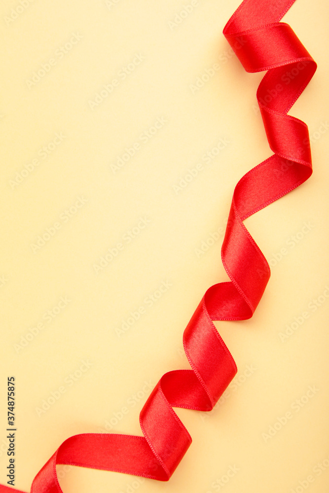 Shiny red ribbon on beige background with copy space. Shiny red ribbon on beige background with copy space.