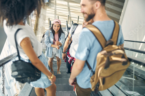 Young happy friends standing on elevator in airport