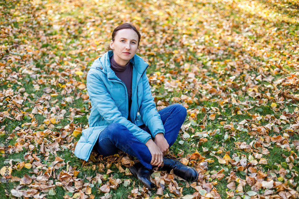 Woman wearing blue jacket sitting in autumn park Woman wearing blue jacket sitting in autumn park