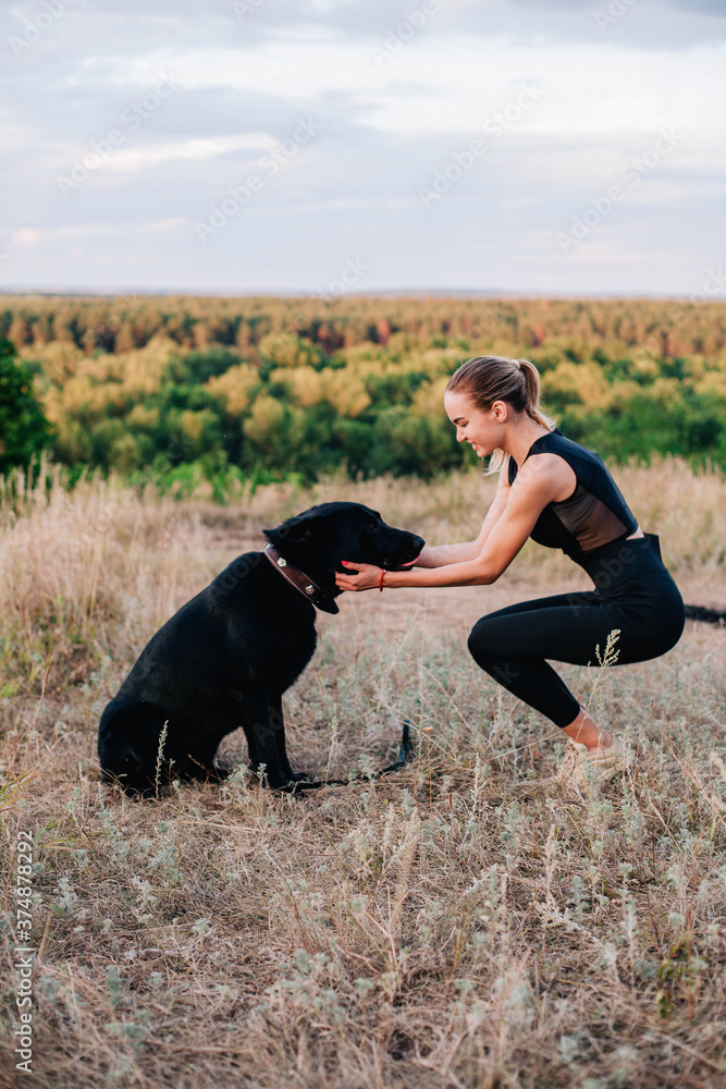 Young slender girl at sunset plays with a sheepdog