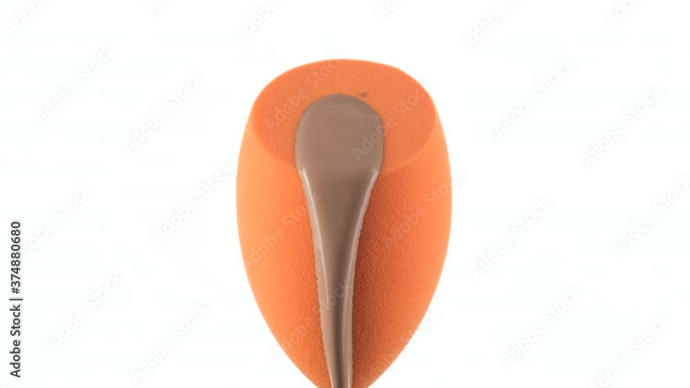 liquid foundation pour on yellow make up blender sponge for apply on face. white background liquid foundation pour on yellow make up blender sponge for apply on face. white background