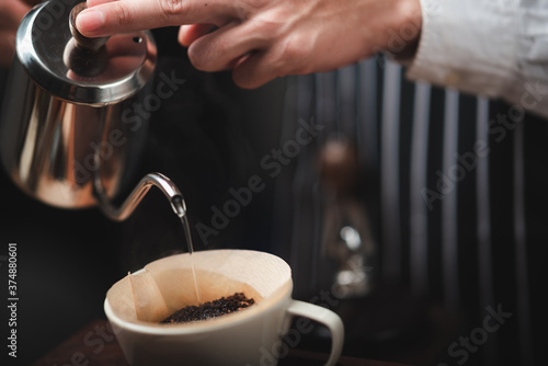 Hand drip coffee filter, barista pouring hot water on roasted coffee ground with filter