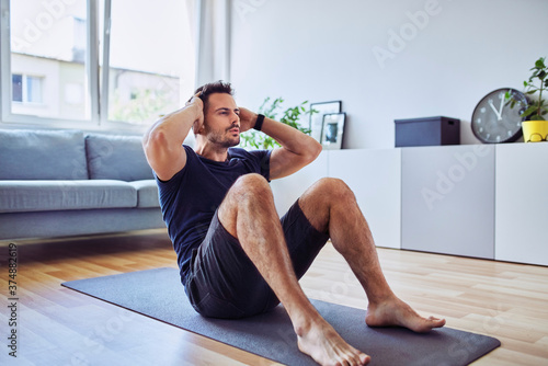 Sporty man doing sit-ups exercise during home workout photo