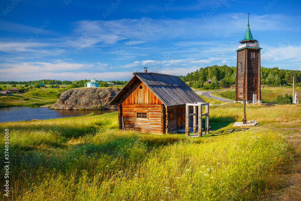 Obraz premium russian countryside with old log house and fire tower
