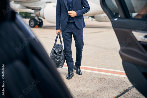 Elegant man carrying a bag walking to a car photo