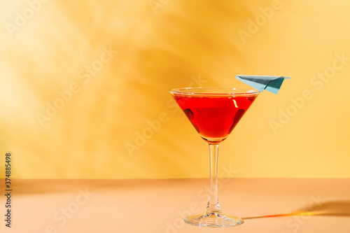 Vacation red cocktail  martini in glass with blue plane  on yellow background
