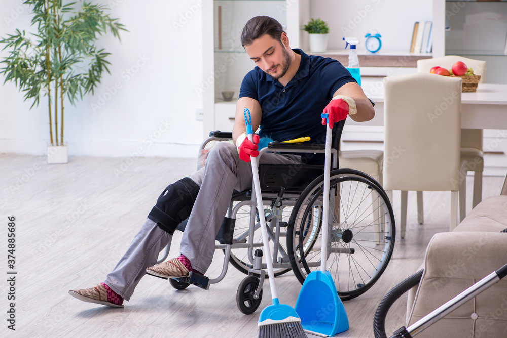 Young leg injured contractor in wheel-chair cleaning the house Young leg injured contractor in wheel-chair cleaning the house
