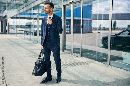 Weary-looking man exits the airport with his bag