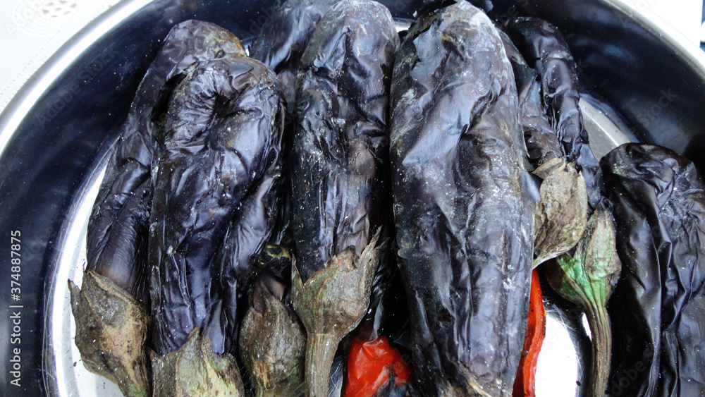 Obraz premium Grilled and roasted whole black eggplants on the metal pot