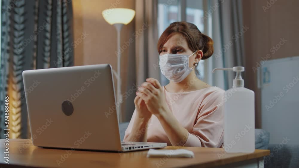 Woman works remotely from home with laptop, disinfects hands with antiseptic Woman works remotely from home with laptop, disinfects hands with antiseptic