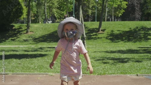 A child wearing a mask plays on a playground during a pandemic.