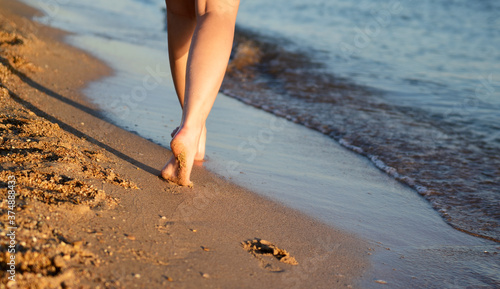 a young girl walks barefoot on the wet sand along the sea shore