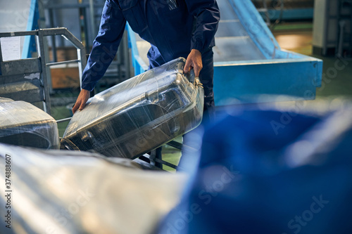Fotografía Luggage handler holding a suitcase while sorting bags