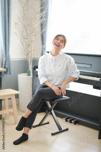 Asian woman sitting in front of an electric piano relaxed