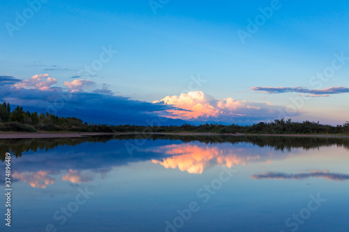 Beautiful sunset by the lake. Bright clouds are reflected in the water. Kyrgyzstan.