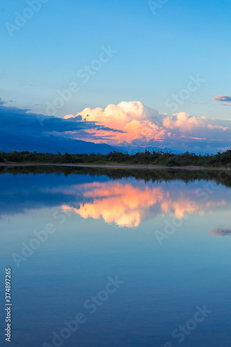 Beautiful sunset by the lake. Bright clouds are reflected in the water. Kyrgyzstan.