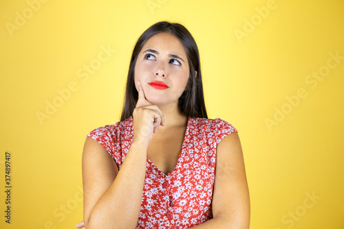 Young beautiful woman over isolated yellow background thinking and looking to the side