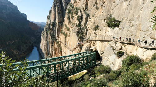 Hikers with helmets on the famous Caminito del Rey footpath, crossing the railway bridge and tunnel near El Chorro, Andalucia, Spain