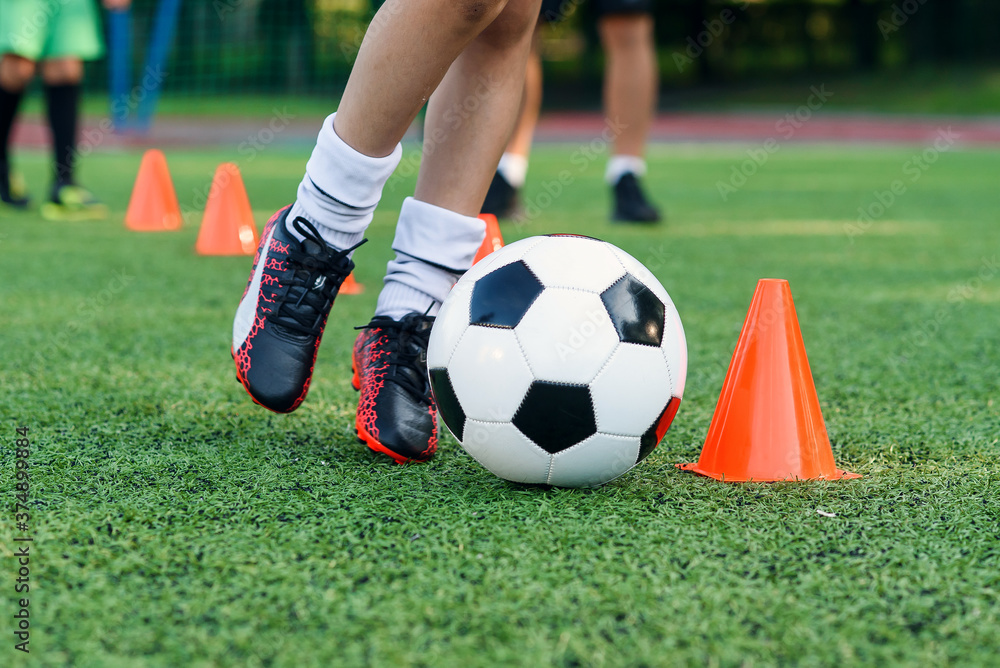 Soccer player kicking ball on field. Soccer players on training session. Close up footballer feet kicking ball on grass. Soccer player kicking ball on field. Soccer players on training session. Close up footballer feet kicking ball on grass.