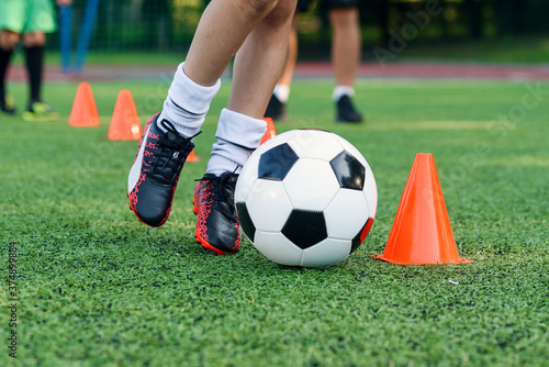 Soccer player kicking ball on field. Soccer players on training session. Close up footballer feet kicking ball on grass.