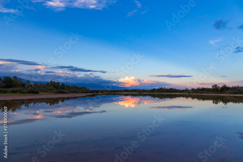 Beautiful sunset by the lake. Bright clouds are reflected in the water. Kyrgyzstan. © Alwih