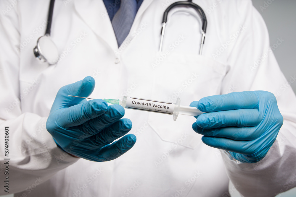 Close up of doctor's hands in medical gloves with a syringe with Covid-19 serum/vaccine Close up of doctor's hands in medical gloves with a syringe with Covid-19 serum/vaccine