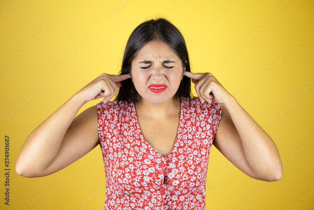 Young beautiful woman over isolated yellow background covering ears with fingers with annoyed expression for the noise of loud music. Deaf concept. Young beautiful woman over isolated yellow background covering ears with fingers with annoyed expression for the noise of loud music. Deaf concept.