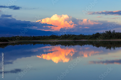 Beautiful sunset by the lake. Bright clouds are reflected in the water. Kyrgyzstan.