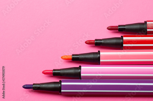 five open markers or pens of pink, purple, pink color lie like steps on a pink background, isolated mock up.