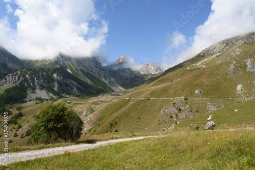 landscape of the mountain peaks of the Alps, rugged and rocky mountains, part of the French Alps mountain range. The sky between clear blue, is covered with white clouds, you can see in the valley the