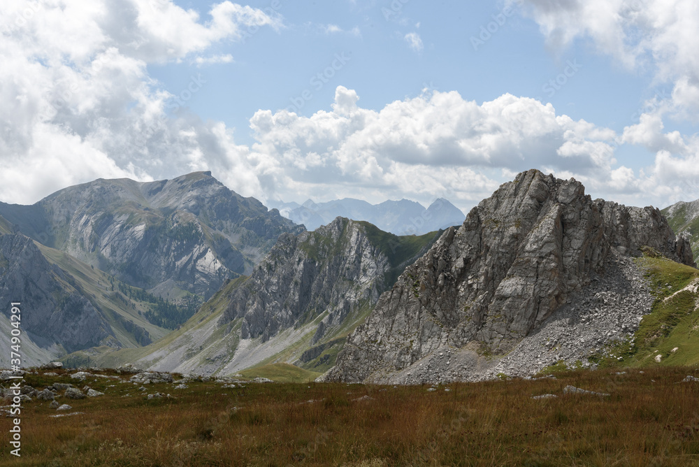 landscape of the mountain peaks of the Alps, rugged and rocky mountains, part of the French Alps mountain range. The sky between clear blue, is covered with white clouds, you can see in the valley the landscape of the mountain peaks of the Alps, rugged and rocky mountains, part of the French Alps mountain range. The sky between clear blue, is covered with white clouds, you can see in the valley the