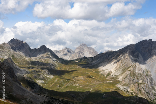 landscape of the valley between mountain peaks of the Alps, rugged and rocky mountains, part of Frrance mountain range. clear blue, is covered with white clouds, 