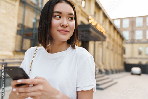 Positive young asian woman walking by street