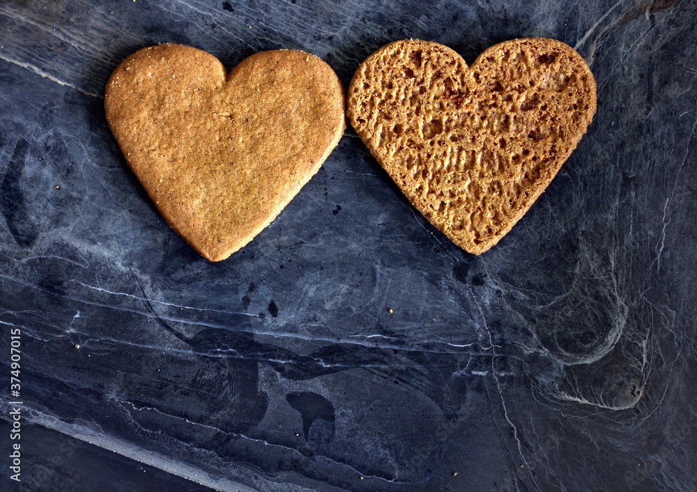 Obraz premium Two hearts cookies on a black and dirty background.