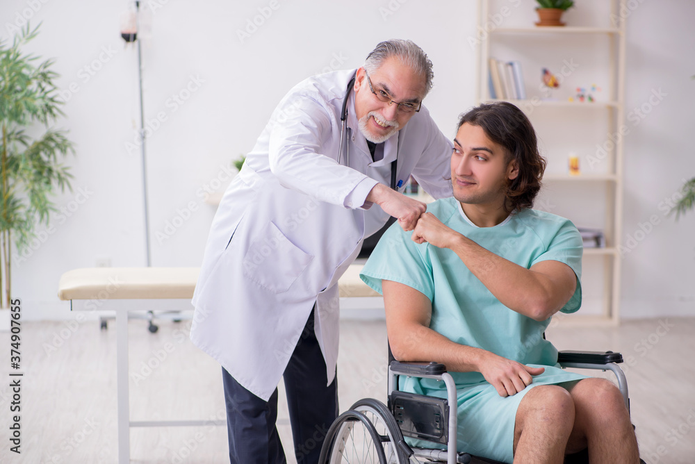 Young male patient in wheel-chair and experienced doctor traumatologist Young male patient in wheel-chair and experienced doctor traumatologist