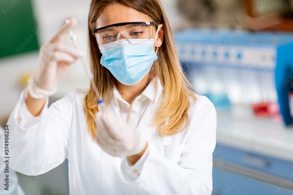 Plakat Woman doctor wearing protective face mask in lab hold needle syringe and medicine vial vaccine bottle