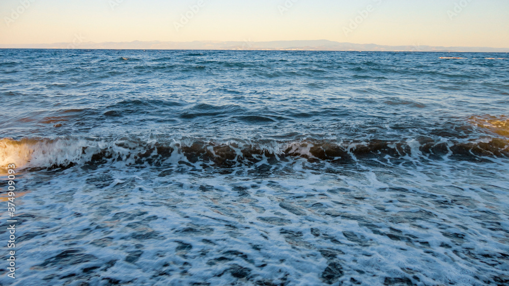The waves breaking on a stony beach. Mediterranean sea waves crashing on the rocks at the beach