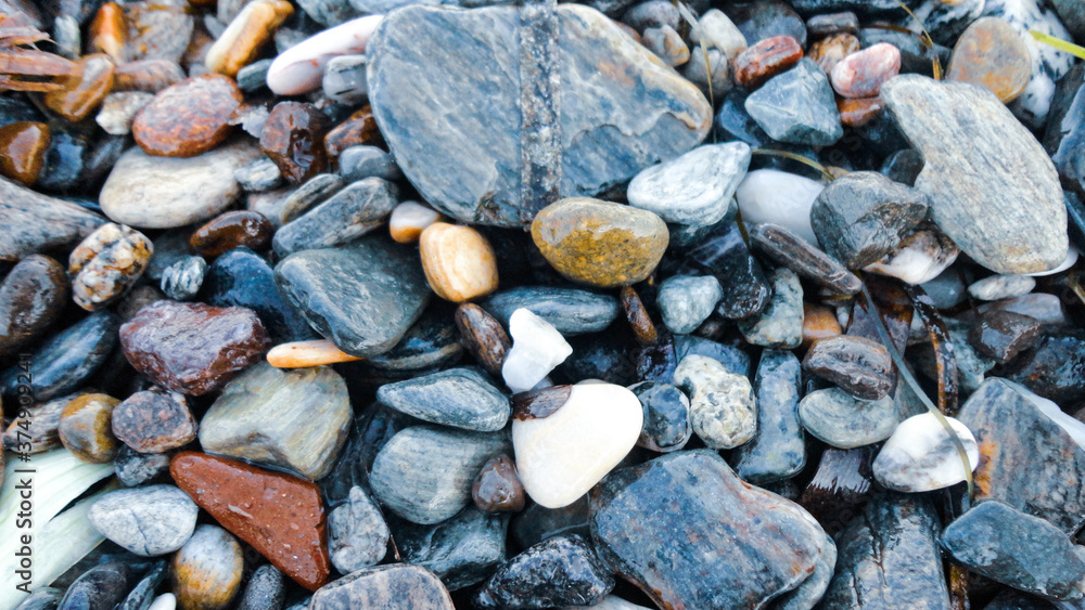 Stony beach on a sunny day. Background of different pebbles from above on the beach Stony beach on a sunny day. Background of different pebbles from above on the beach