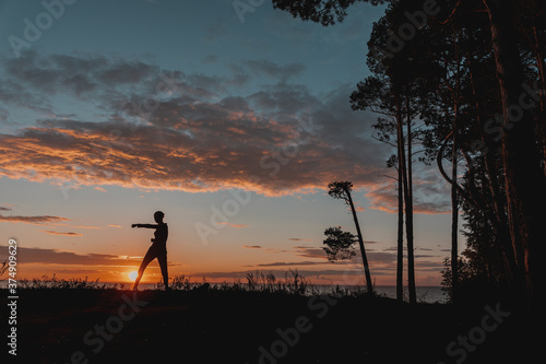 the girl is engaged in karate on the background of the setting sun 