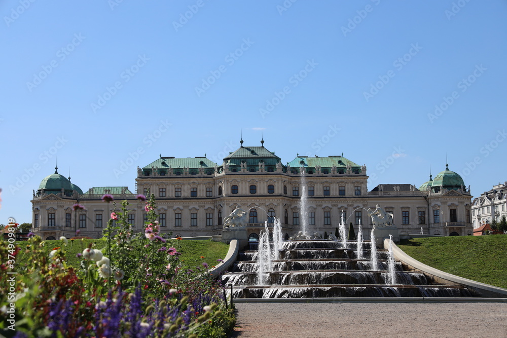 Fototapeta premium Schloss Belvedere vor einem künstlichen Wasserbrunnen und wunderschönen Blumen im Sommer