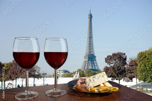 Wallpaper Mural Two glasses of red wine with snacks assortment on view of Paris and Eiffel tower. Glass of red wine with different snacks - plate with ham, sliced, blue cheese. Couple romantic celebration. Torontodigital.ca