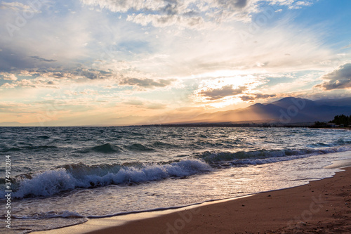 Beautiful sunset by the lake. Bright clouds are reflected in the water. Kyrgyzstan.